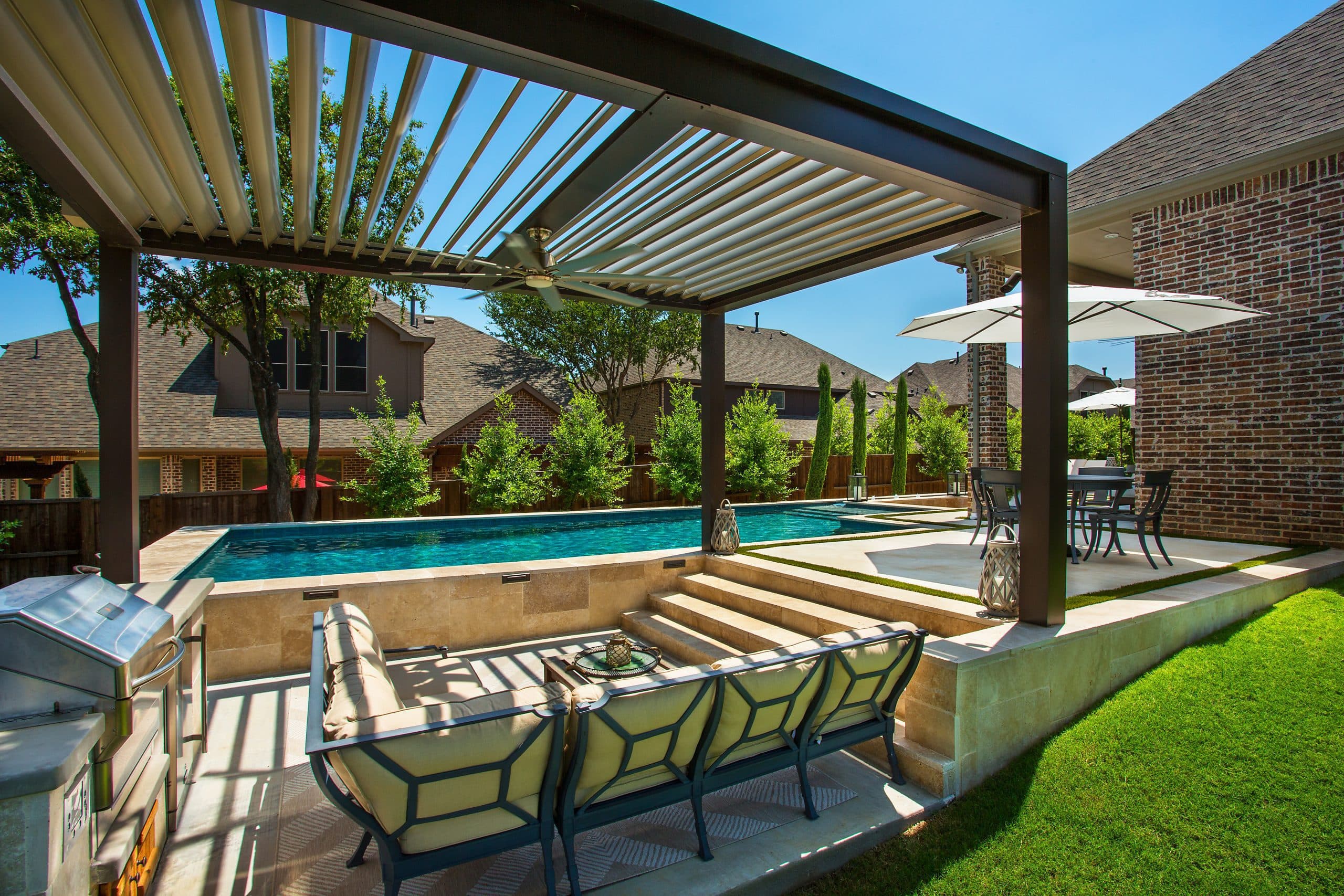 Equinox louvered roof over a backyard pool, louvers half open